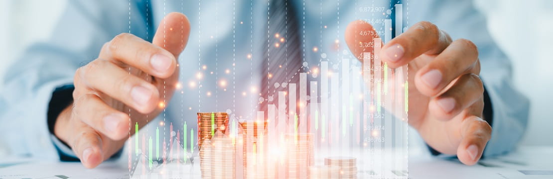Businessman holds his hands above his desk, surrounding a pile of coins and an animated financial chart.
